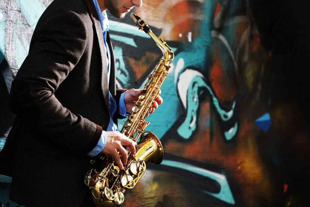 young-man-with-saxophone-outside-near-old-painted-wall-1024x683